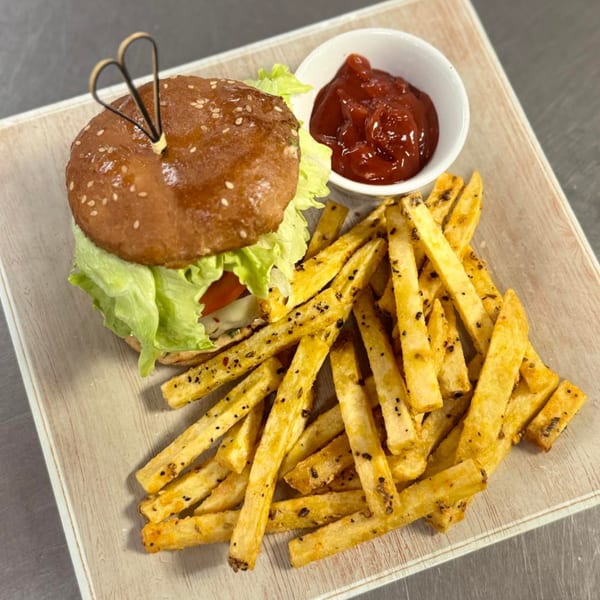 A hamburger with lettuce and tomato, served with seasoned fries and a side of ketchup.